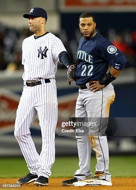 Derek Jeter of the New York Yankees taps Robinson Cano of the Seattle Mariners as Cano stands on second base on April 29, 2014 at Yankee Stadium in...