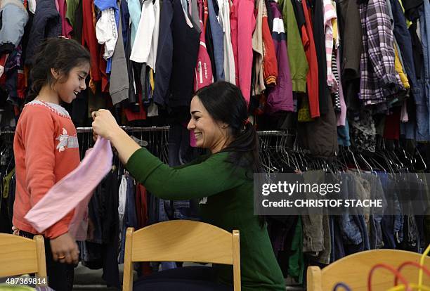 Helper and a migrant girl from Syria laugh in "Bayernkaserne", where donations for refugess have been collected, in Munich, southern Germany, on...