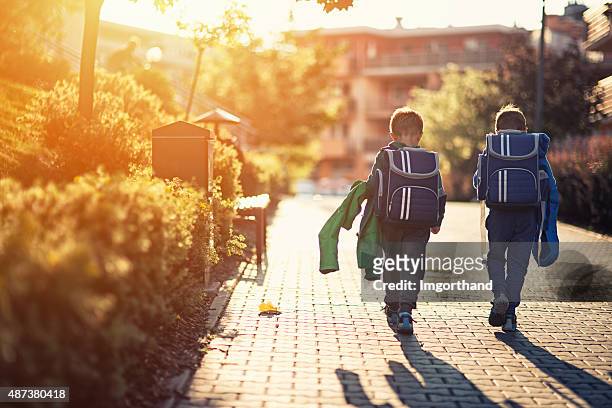 two little boys returning from school - school district stock pictures, royalty-free photos & images