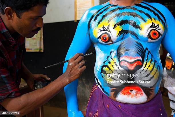 Performer is getting body-painted as a tiger for Puli Kali in Thrissur. Puli Kali is a colorful recreational folk art performed in Kerala in India....