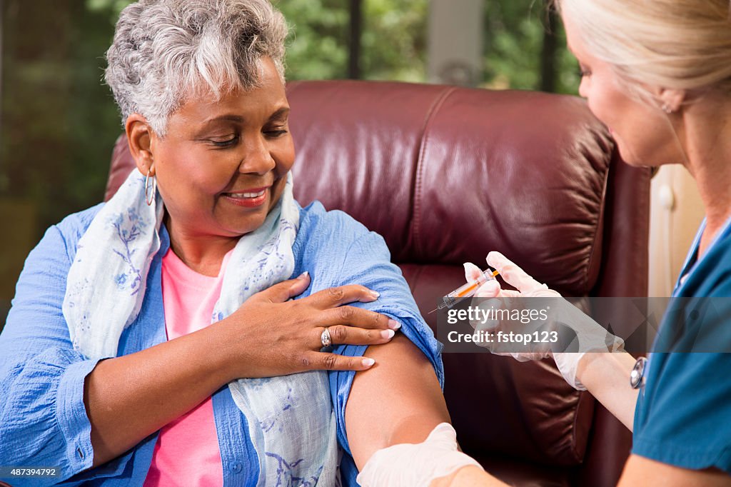 Home healthcare nurse giving injection to senior adult woman.