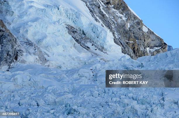 In this photograph taken on April 18 survivors work to dig free and assist the injured following an avalanche that killed sixteen Nepalese sherpas in...