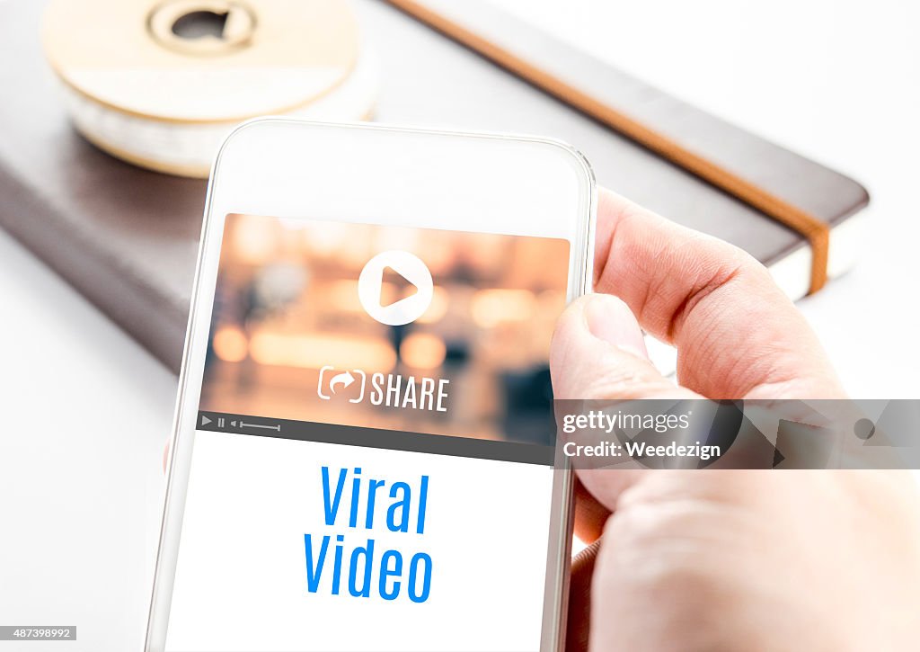 Close up hand holding smart phone with Viral Video word