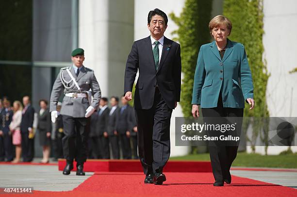 German Chancellor Angela Merkel and Japanese Prime Minister Shinzo Abe prepare to review a guard of honour upon Abe's arrival at the Chancellery on...