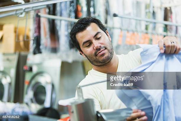 hispanic man working in a dry cleaner - dry cleaning shop stock pictures, royalty-free photos & images