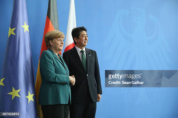German Chancellor Angela Merkel and Japanese Prime Minister Shinzo Abe shake hands after speaking to the media following talks at the Chancellery on...