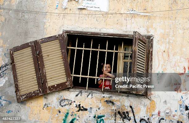 Palestinian girl looks from a window at militants from the Popular Front for the Liberation of Palestine during a parade in Khan Yunis in the...