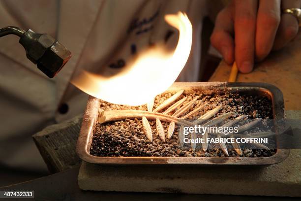 An employee of Swiss Jeweller Chopard uses a blowtorch to heat a Palme d'Or trophy 09 May 2007 at the company's headquarters in Geneva. The...