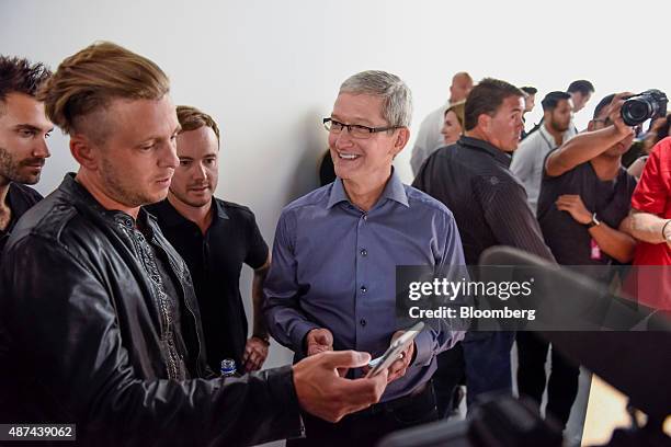 Tim Cook, chief executive officer of Apple Inc., right, speaks with Ryan Tedder, lead singer of One Republic, as other members of the band look on...