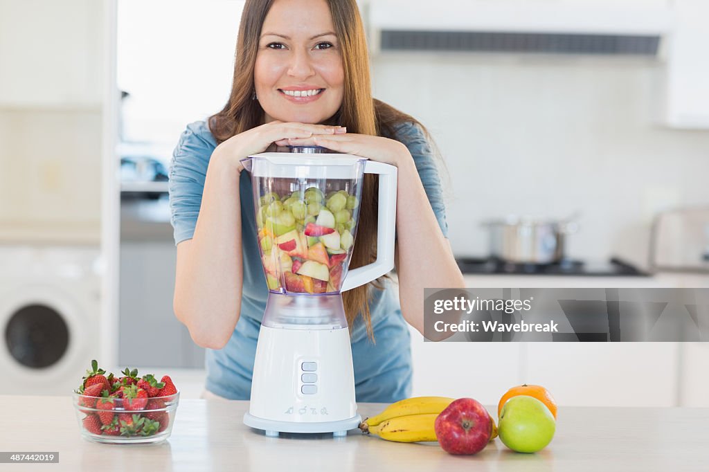 Smiling cute woman posing with a blender in kitchen