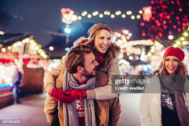 casal tendo diversão ao ar livre no inverno justa. - natal casal imagens e fotografias de stock