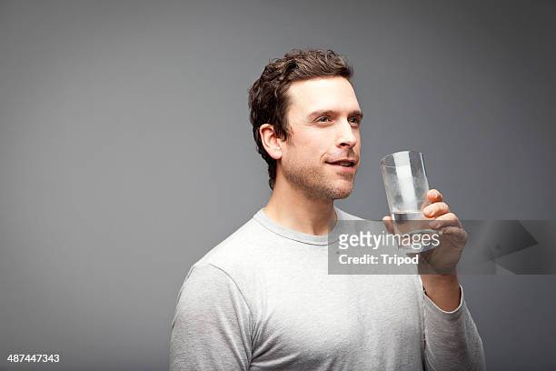 man holding glass of water, smiling - refreshment photos et images de collection