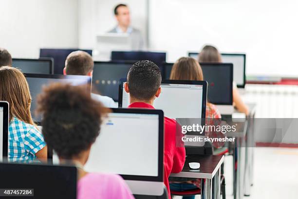 rear view of group of people in a computer lab. - computer training stock pictures, royalty-free photos & images