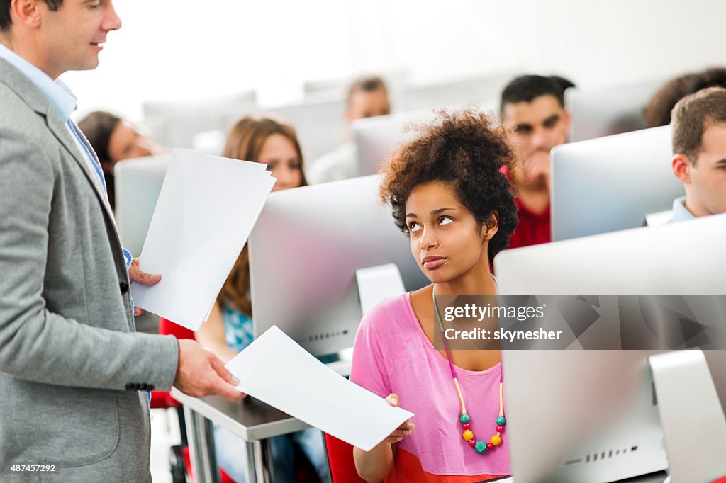 Teacher giving test results to students at computer class.