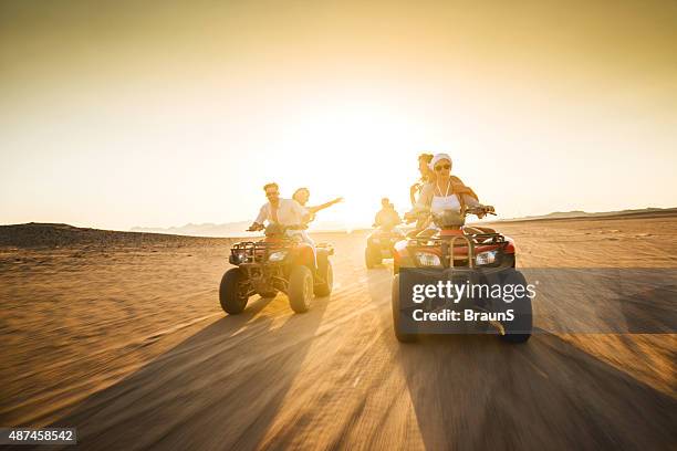 young friends having fun on quad bikes at sunset. - quadbike stock pictures, royalty-free photos & images