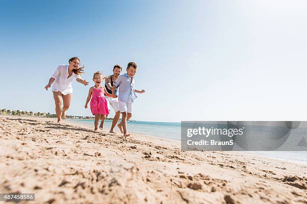 young playful family chasing on the beach during summer day. - family at beach stockfoto's en -beelden