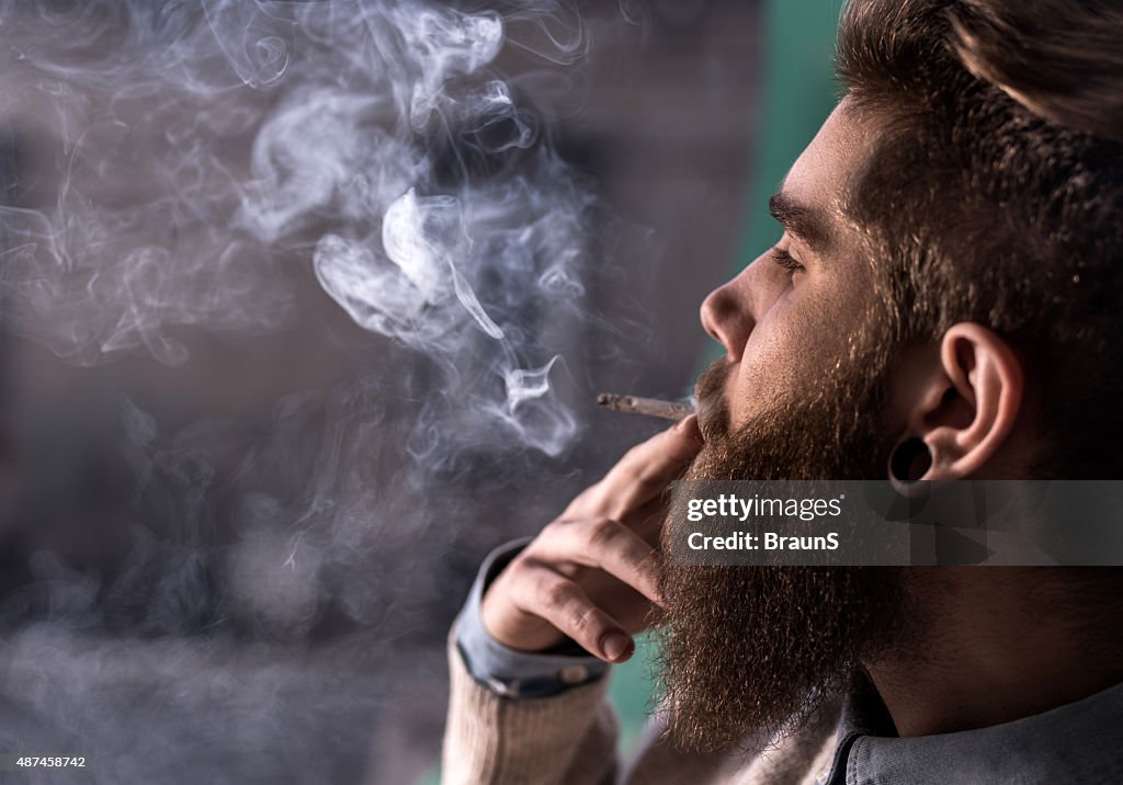 Close up of a young hipster smoking cigarette.