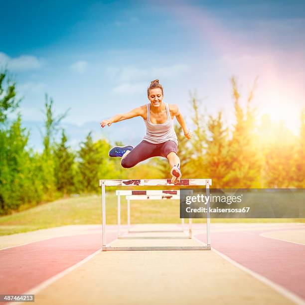weibliche konkurrenten jumping dem hindernislauf hindernis - hindernislauf laufdisziplin stock-fotos und bilder