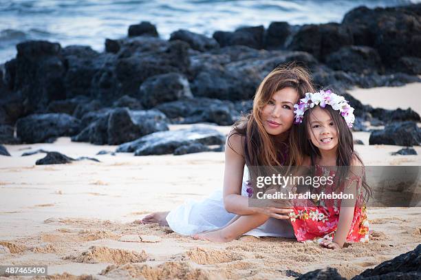 beautiful mother and daughter wearing lei on hawaiian beach - hawaiian lei stockfoto's en -beelden