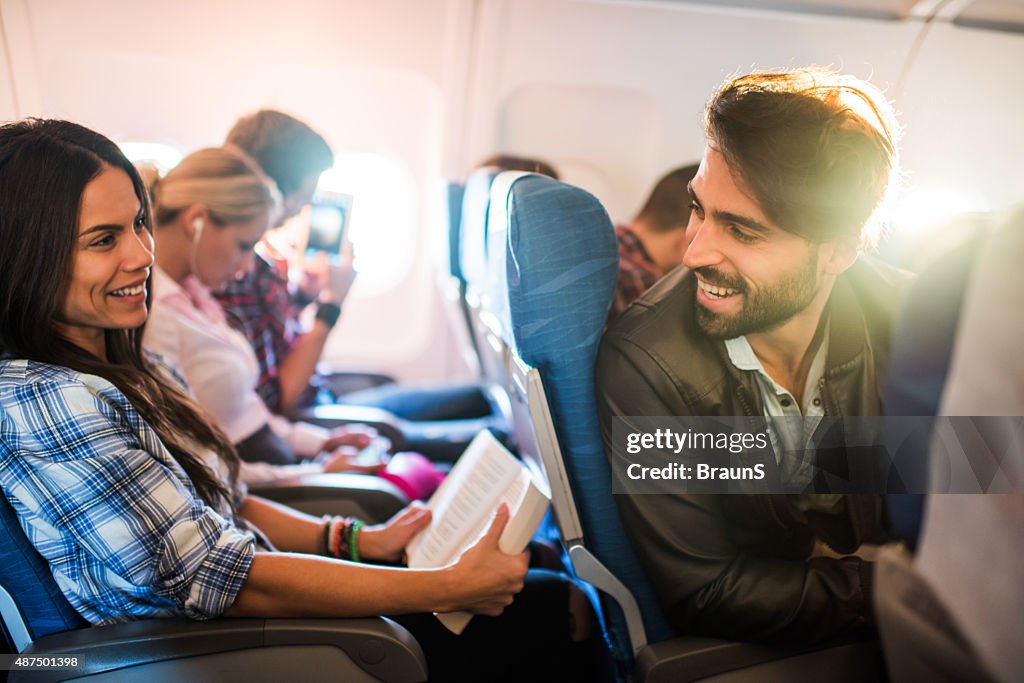 Young smiling man flirting with beautiful woman in airplane.