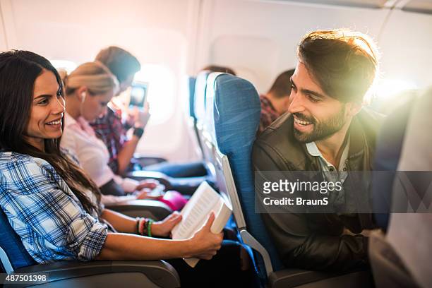 young smiling man flirting with beautiful woman in airplane. - ekonomiklass bildbanksfoton och bilder