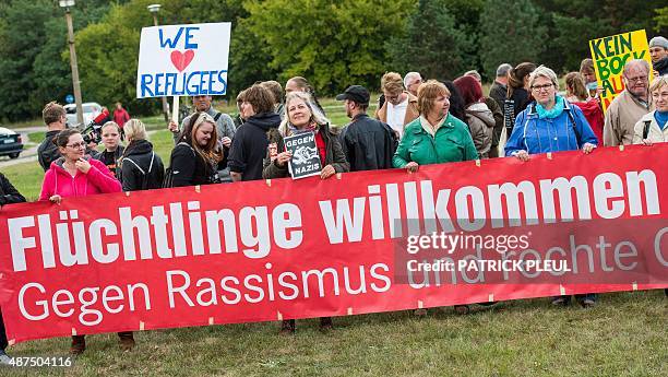 People hold up a banner which reads "Refugees welcome - Against rasicm" during a rally at the registry center for refugees in Eisenhuettenstadt on...