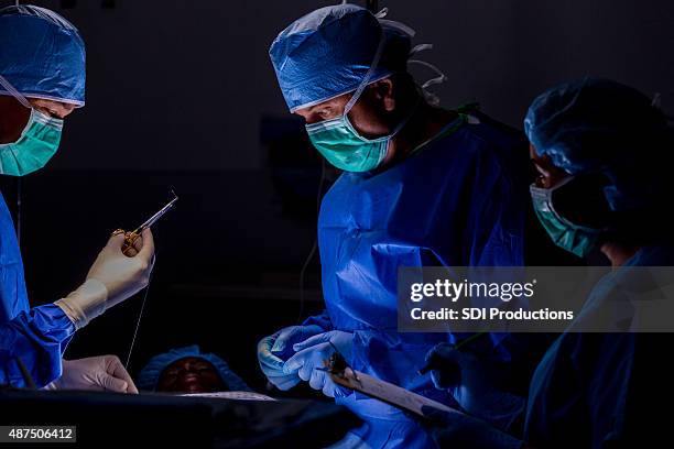 team of surgeons operating on patient in hospital, using sutures - hecht stockfoto's en -beelden