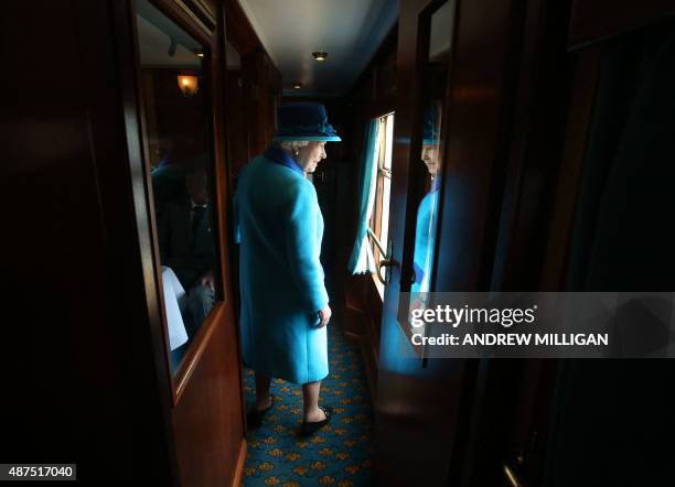 Britain's Queen Elizabeth II looks out of a window as she travels on a train pulled by the steam locomotive 'Union of South Africa' between...