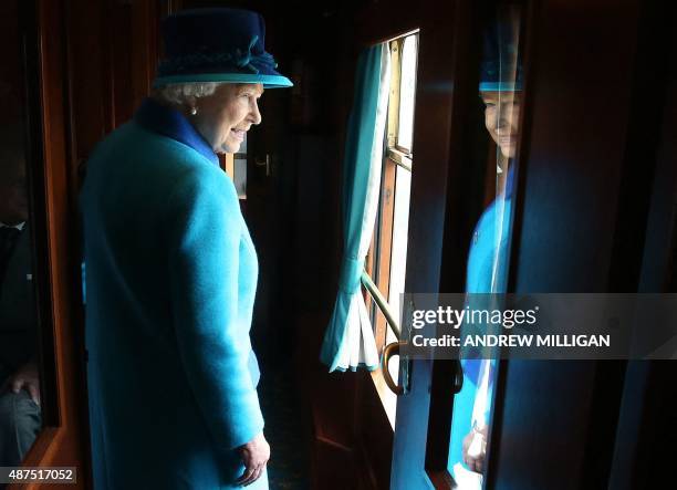 Britain's Queen Elizabeth II looks out of a window as she travels on a train pulled by the steam locomotive 'Union of South Africa' between...