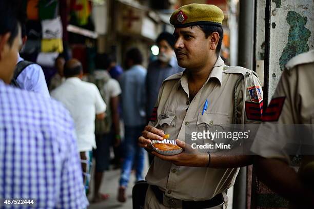 Policeman eats jalebi at the old famous Jalebi wala at the corner of Dariba in Chandni Chowk, on August 20, 2014 in New Delhi, India. Chandni Chowk ,...