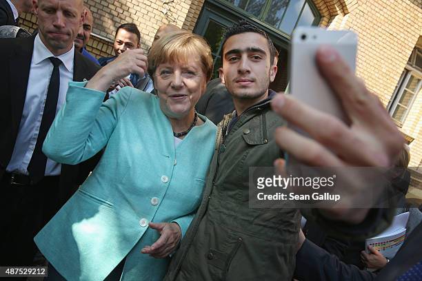 German Chancellor Angela Merkel poses for a selfie with Anas Modamani, a refugee from Syria, after she visited the AWO Refugium Askanierring shelter...