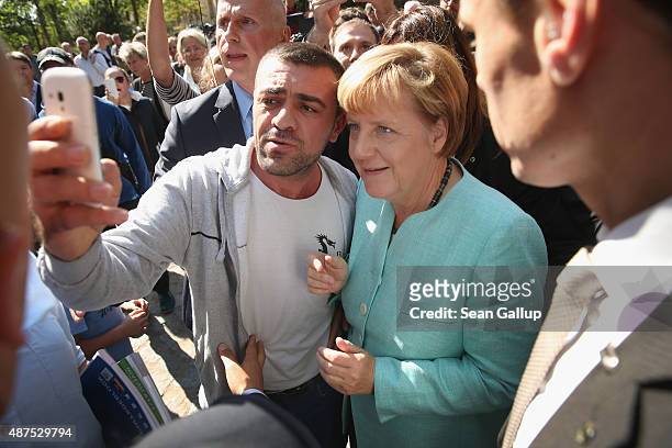 German Chancellor Angela Merkel pauses for a selfie with a migrant after she visited the AWO Refugium Askanierring shelter for migrants on September...
