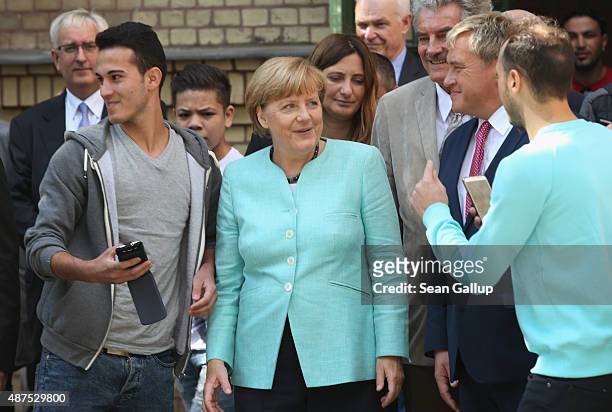 German Chancellor Angela Merkel smiles to a migrant asking for a selfie after she visited the AWO Refugium Askanierring shelter for migrants on...