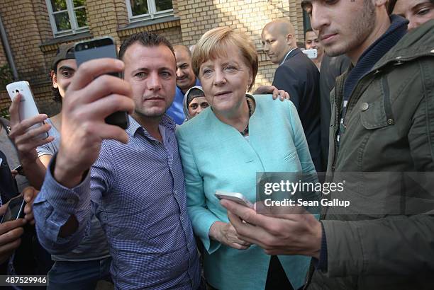 German Chancellor Angela Merkel pauses for a selfie with a migrant before she visited the AWO Refugium Askanierring shelter for migrants on September...