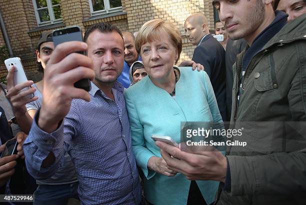 German Chancellor Angela Merkel pauses for a selfie with a migrant before she visited the AWO Refugium Askanierring shelter for migrants on September...