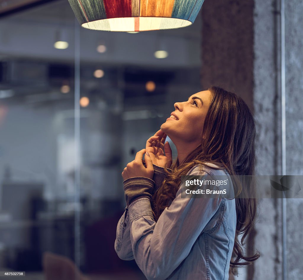 Young happy woman standing and looking at lamp.