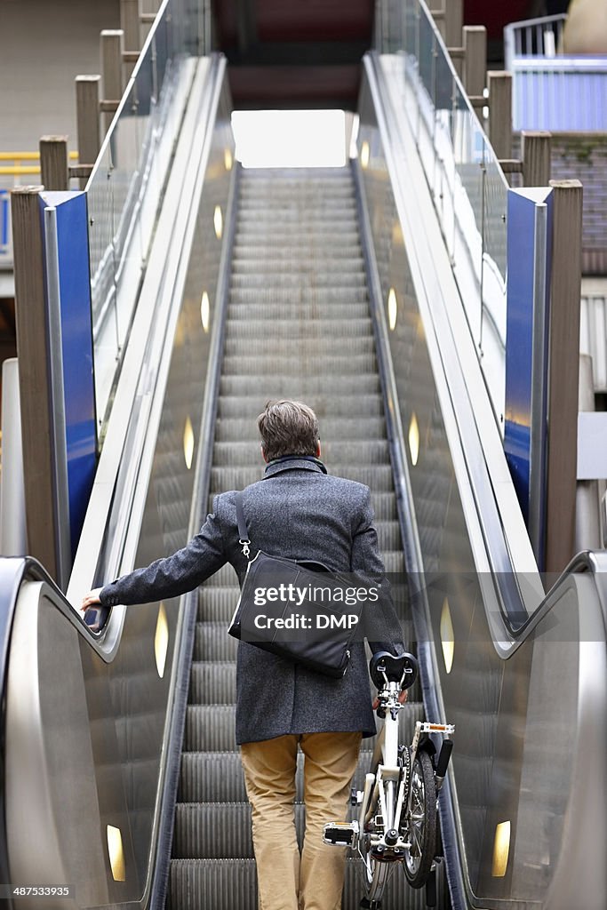 Businessman with folding bicycle on escalator