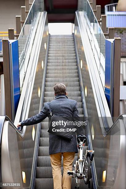 businessman with folding bicycle on escalator - foldable stock pictures, royalty-free photos & images