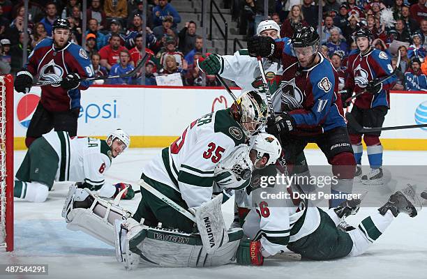 Goalie Darcy Kuemper of the Minnesota Wild knocks down the puck and covers it as he collides with teammate Erik Haula of the Minnesota Wild and Jamie...