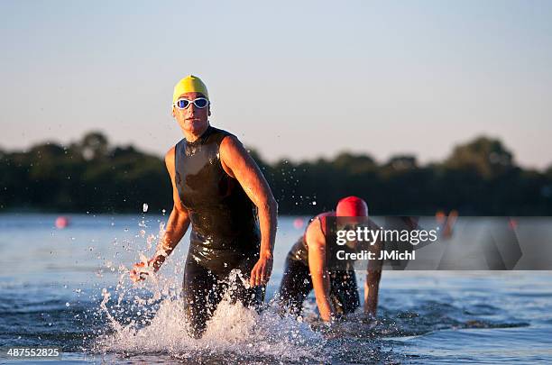 triathlon participants running in the water. - triathlon swim stock pictures, royalty-free photos & images