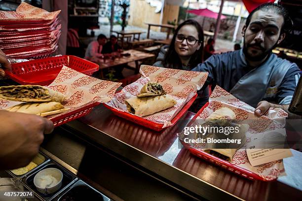 David Barquet, owner and chef of the Camello Gitano Lebanese food truck, right, grabs orders for customers at the Street Food Center in a park in the...