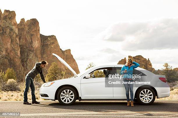 a couple with car trouble. - vehicle hood stock-fotos und bilder