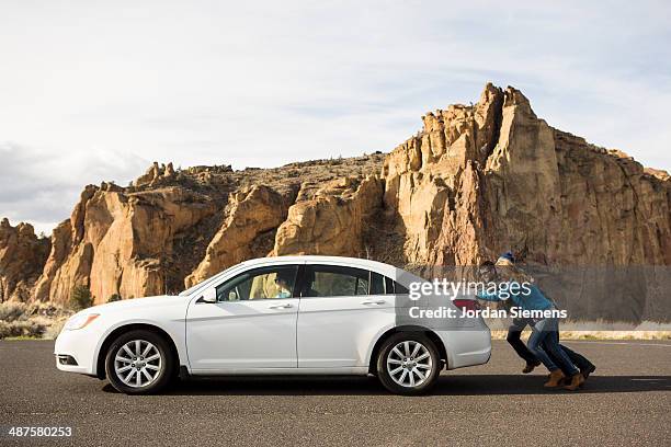 pushing a broken down car. - four people in car stock pictures, royalty-free photos & images