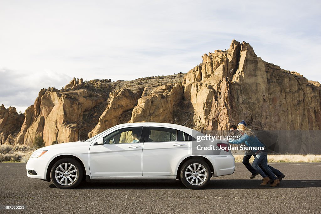 Pushing a broken down car.