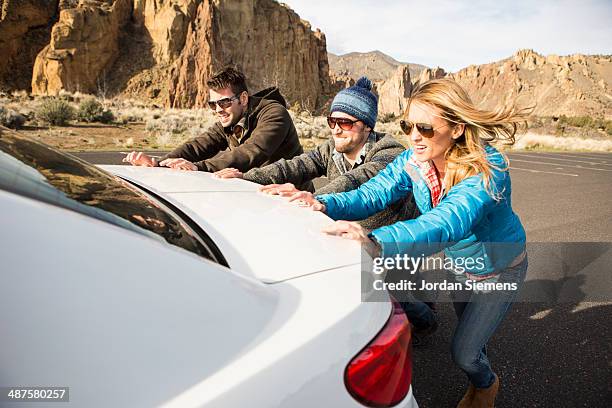 pushing a broken down car. - 3 guy friends road trip stock-fotos und bilder