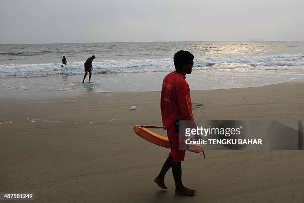 In this photograph taken on April 27 an Indian lifeguard walks along the beachfront as holidaymakers take a dip at Arrosim Beach in Cansaulim,...