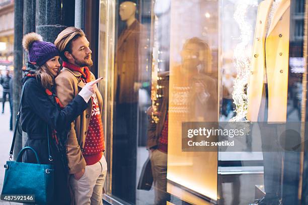 couple window shopping outdoors in winter city street. - window shopping stock pictures, royalty-free photos & images