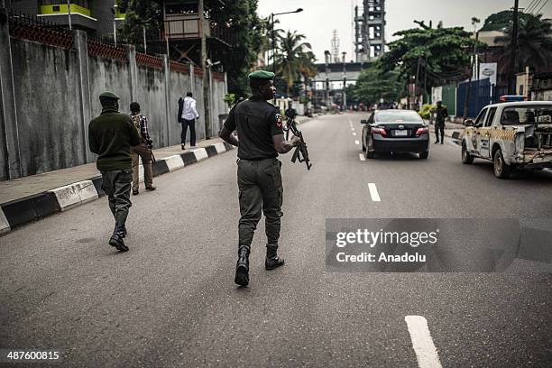 Nigerian ssecurity forces stand guard as demonstrators march during a rally to demand government to rescue schoolgirls abducted by suspected Boko...