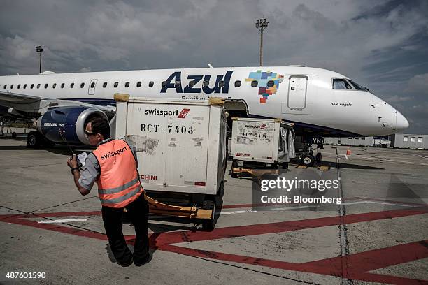 Ground crew member pulls a cart of baggage from an Azul Linhas Aereas Brasileiras SA jet at Viracopos International Airport in Campinas, Brazil, on...