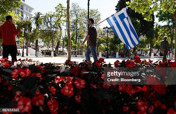 Protestor carries a Greek national flag as he walks across Syntagma square during May Day protests in Athens, Greece, on Thursday, May 1, 2014....